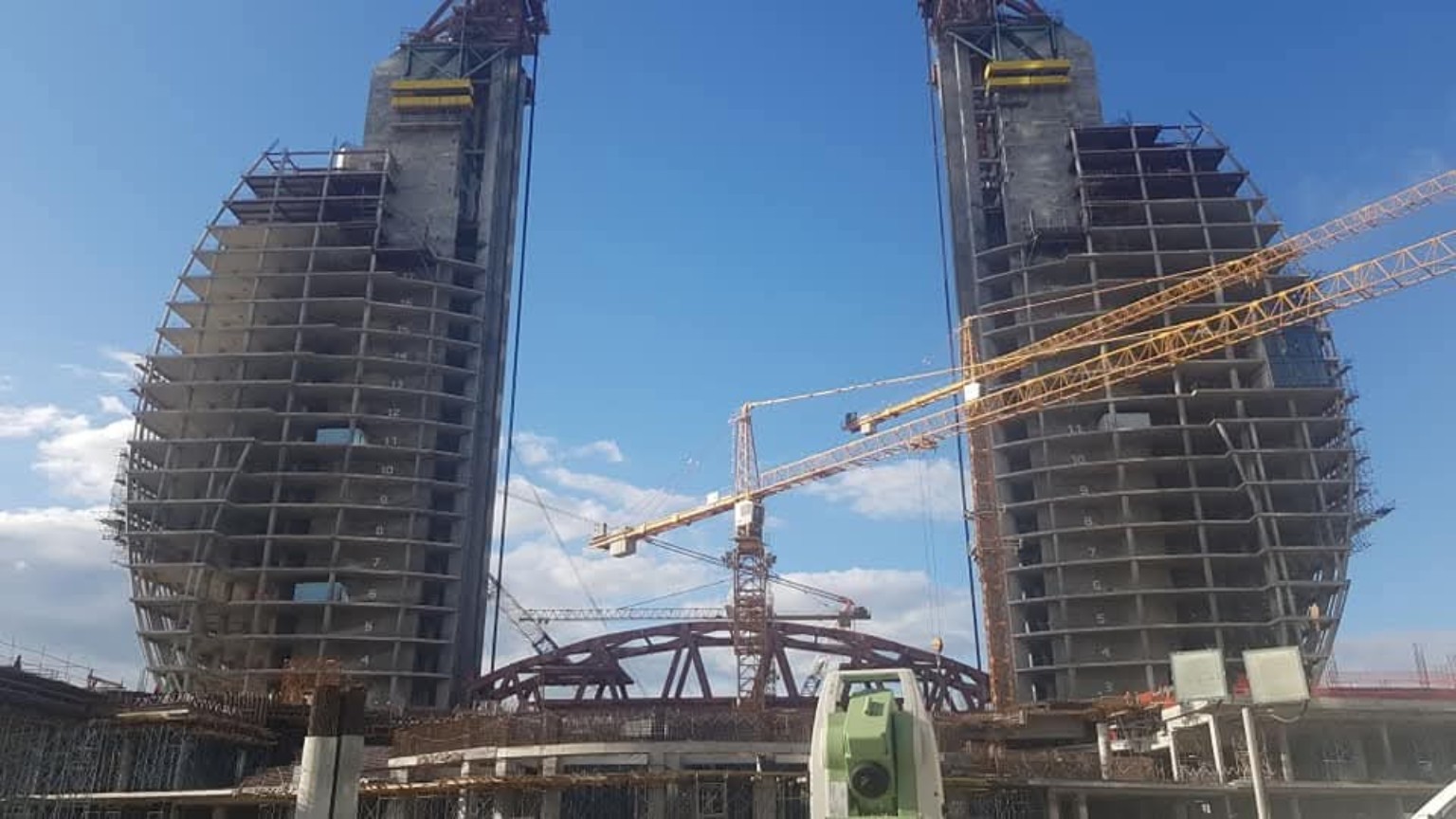 Şəkil 1. Crescent layihəsinin tikinti mərhələsindən real görüntü. Ön planda elektron taxeometr, arxa planda tikilməkdə olan konstruksiyalar görünür. Foto tikinti ölçmələrinin aparıldığı sahə şəraitini göstərir.